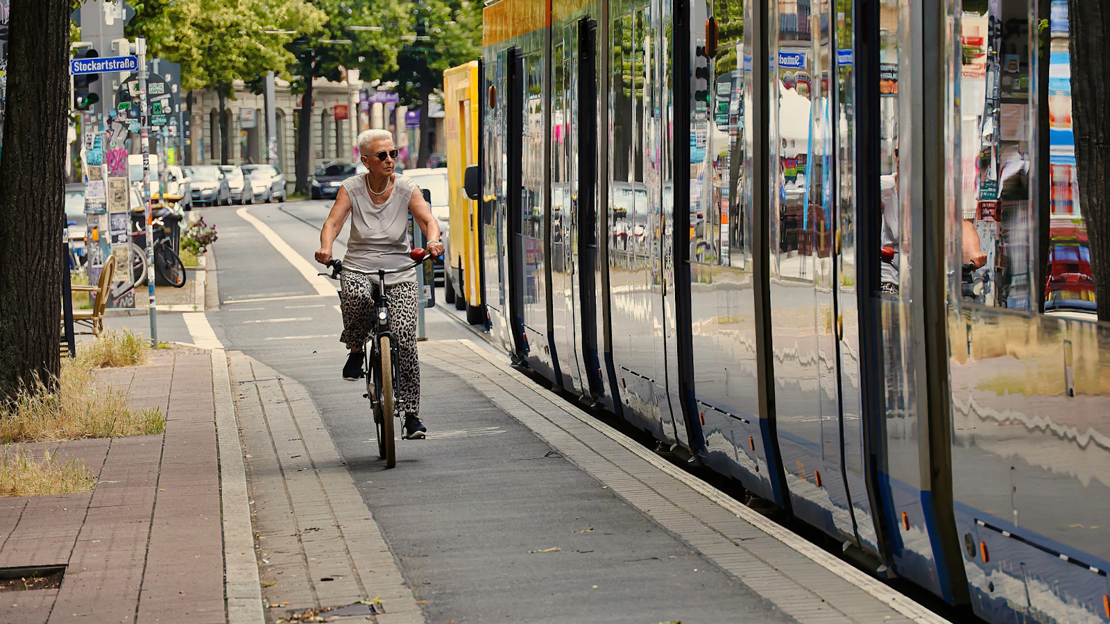Vrouw fietst langs tramrails in de stad op een heldere dag.
