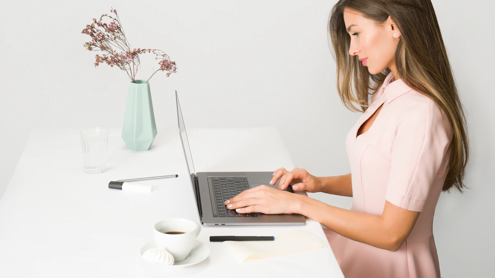 Vrouw kijkt nadenkend weg achter haar laptop.