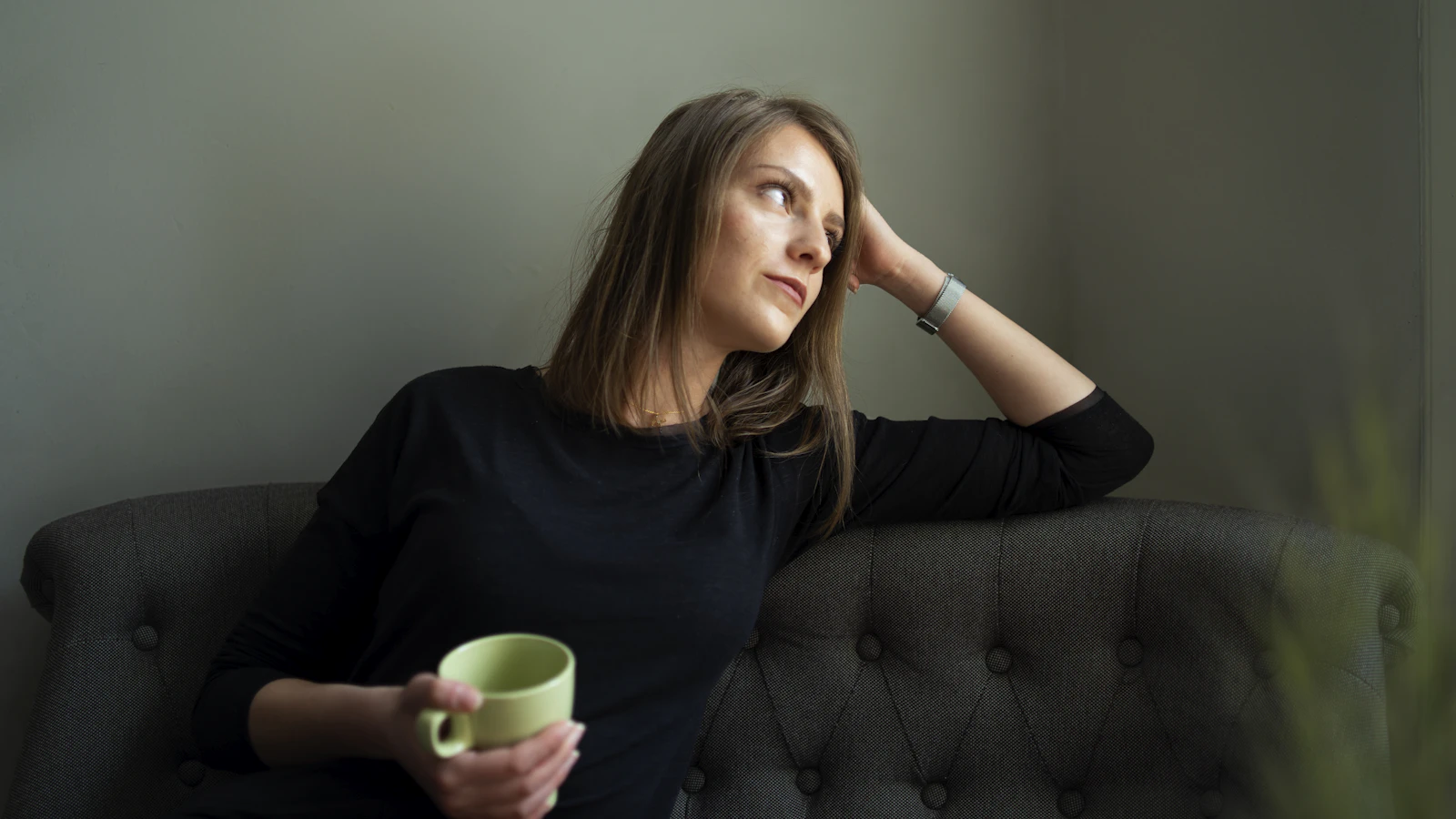 Vrouw met een mok rust uit op de bank.