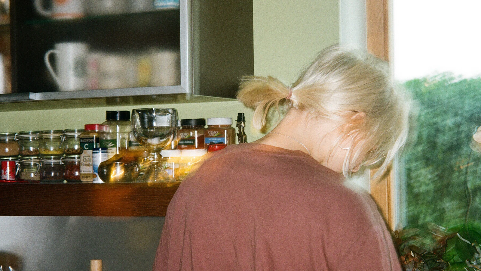 Vrouw met blond haar in haar keuken bij daglicht.