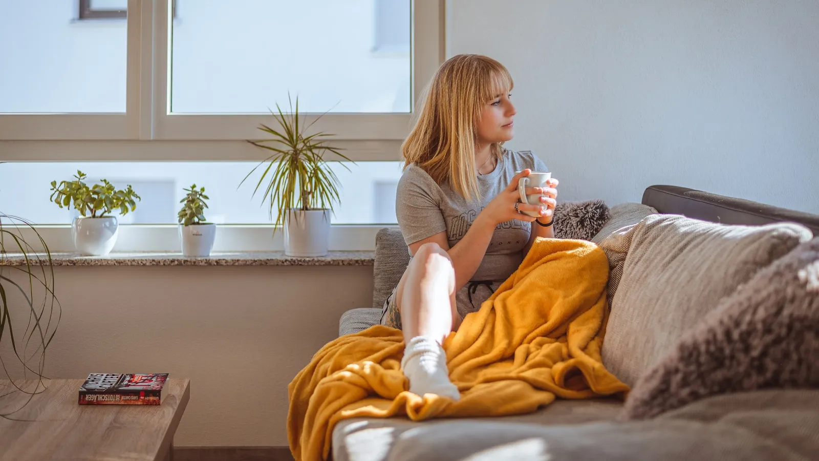 Vrouw houdt haar onderbuik vast vanwege hevige menstruatiepijn op de bank.