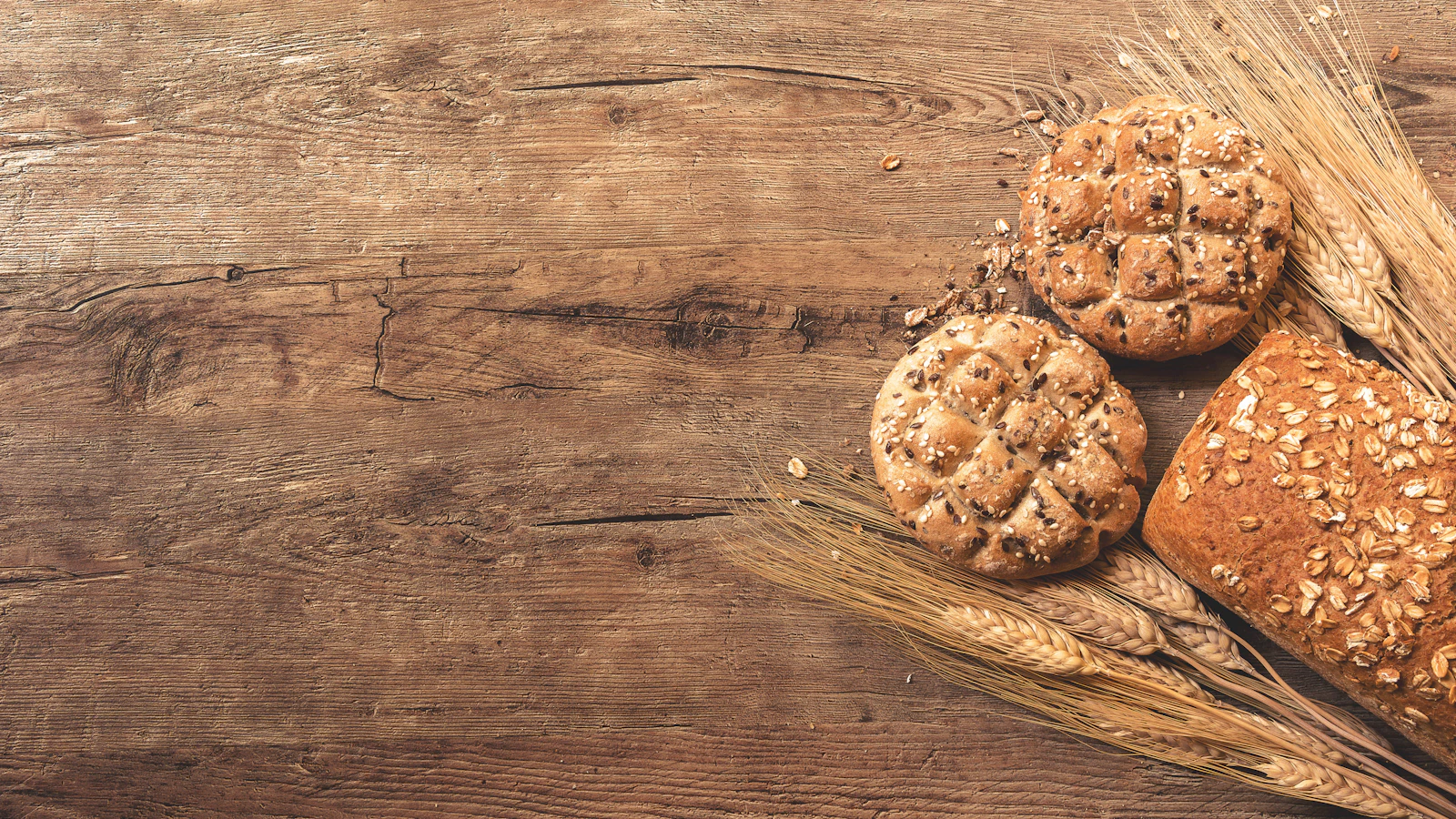 Broodjes en tarwearen op een houten tafel.