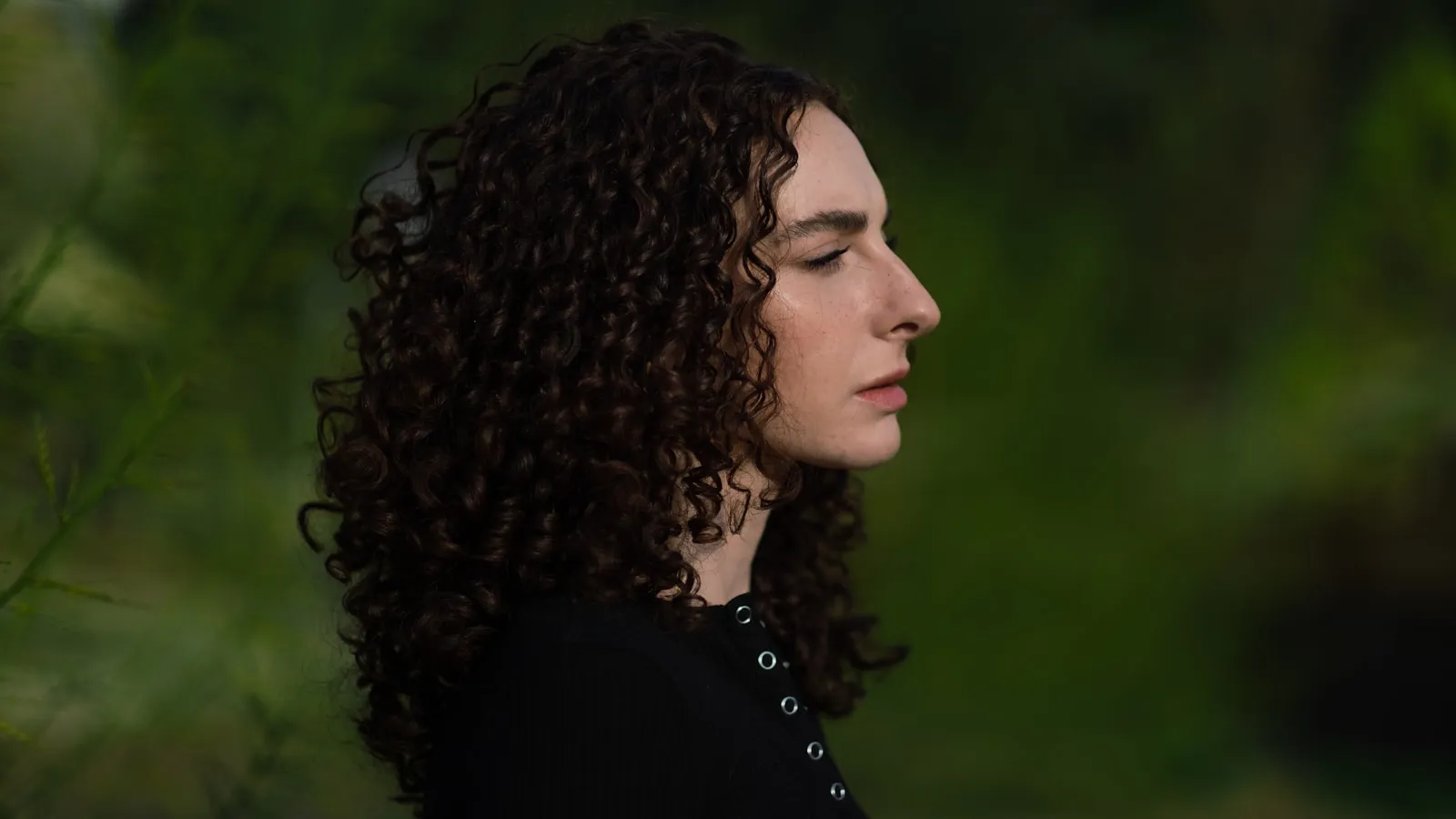 Vrouw kijkt rustig weg bij daglicht in een gewone omgeving.