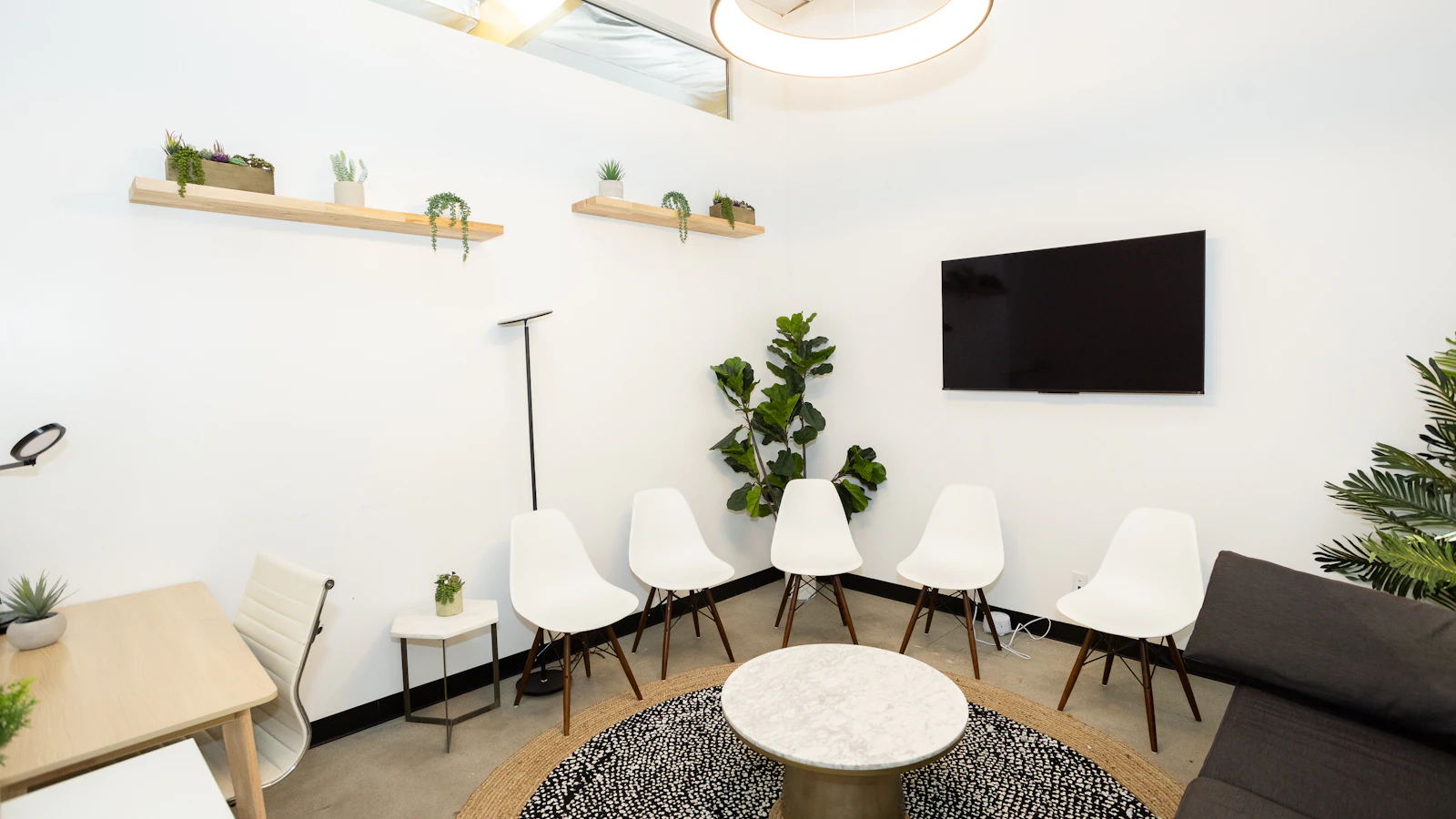 Moderne wachtruimte met witte stoelen en planten.