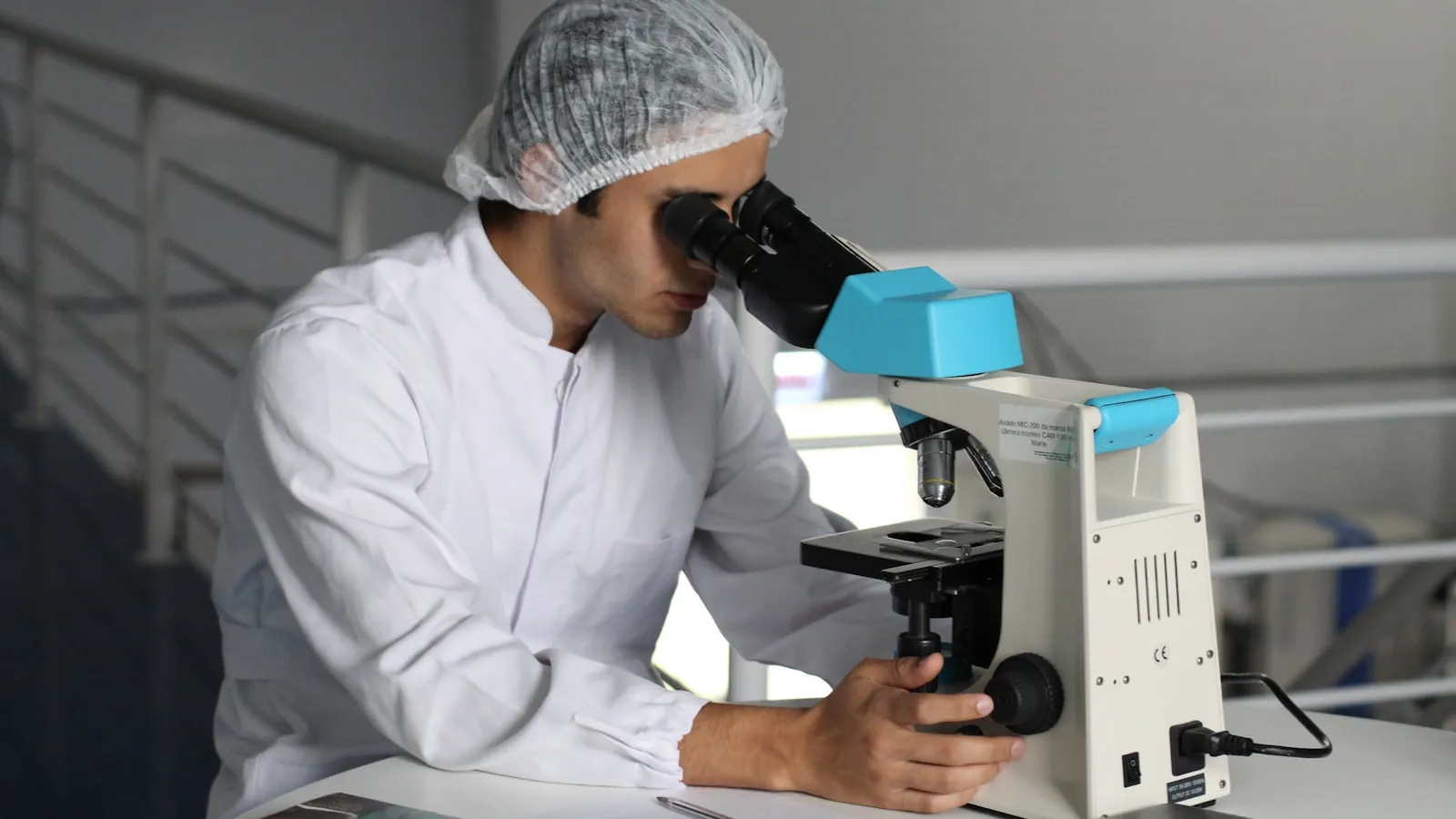 Laborant kijkt door een microscoop in een laboratorium.