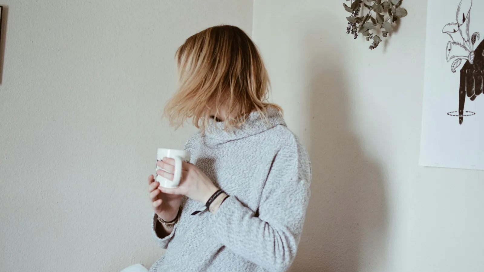 Vrouw met een mok in een rustige, lichte ochtendkamer.