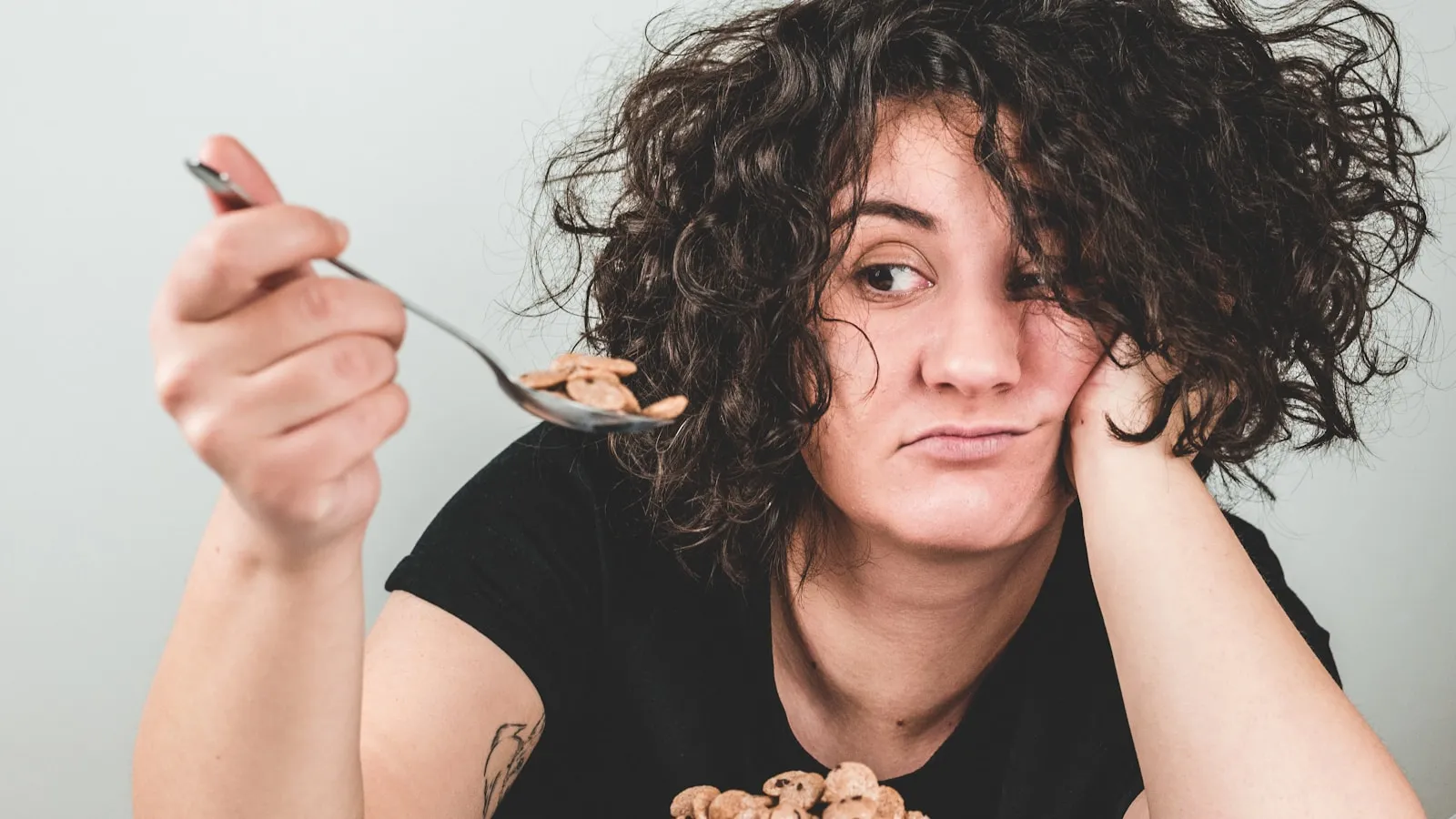 Vrouw met donkergroene bladgroente en noten als bronnen van magnesium op tafel