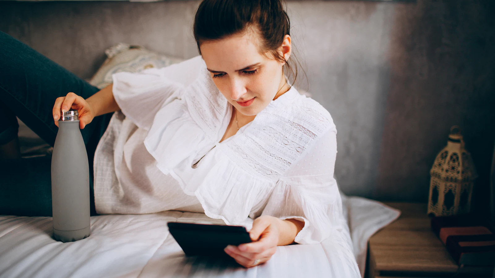Vrouw rust met een warme kruik op de bank in de week voor haar menstruatie.