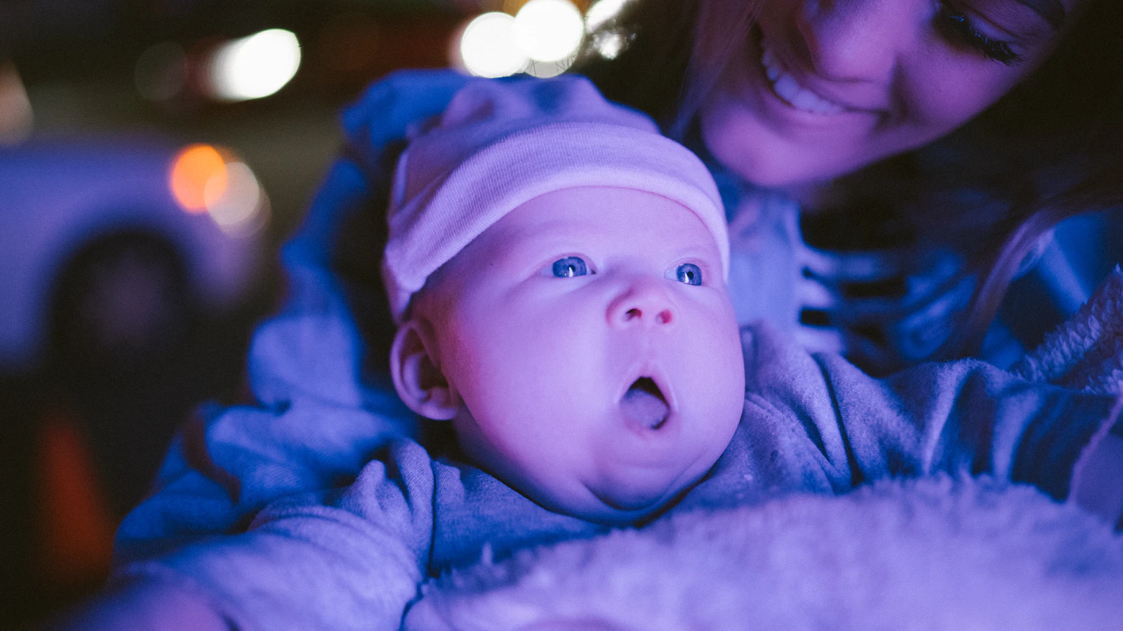 Vermoeide moeder houdt haar baby vast bij een raam.