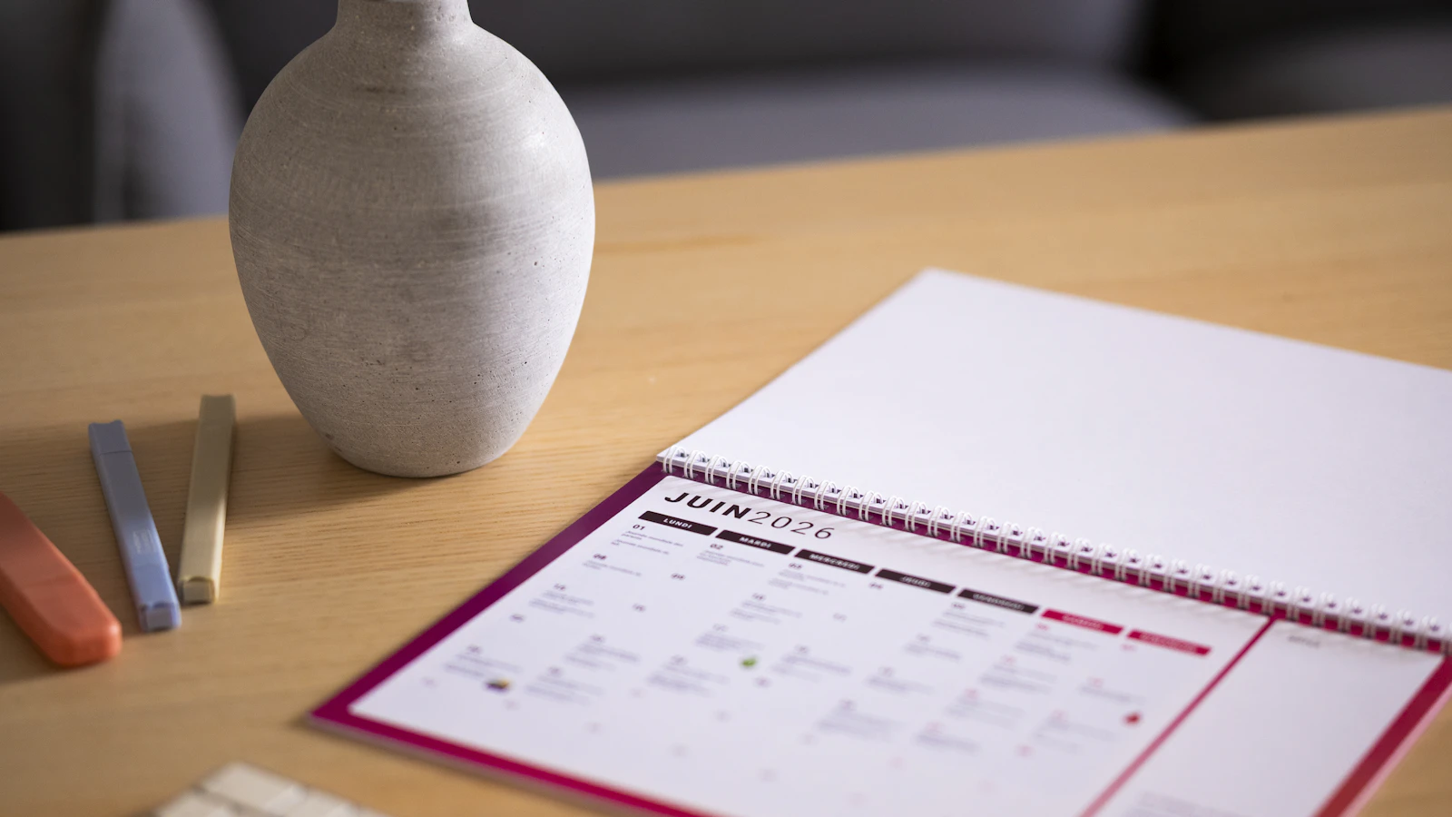 Kalender en vaas op een houten bureau bij daglicht.