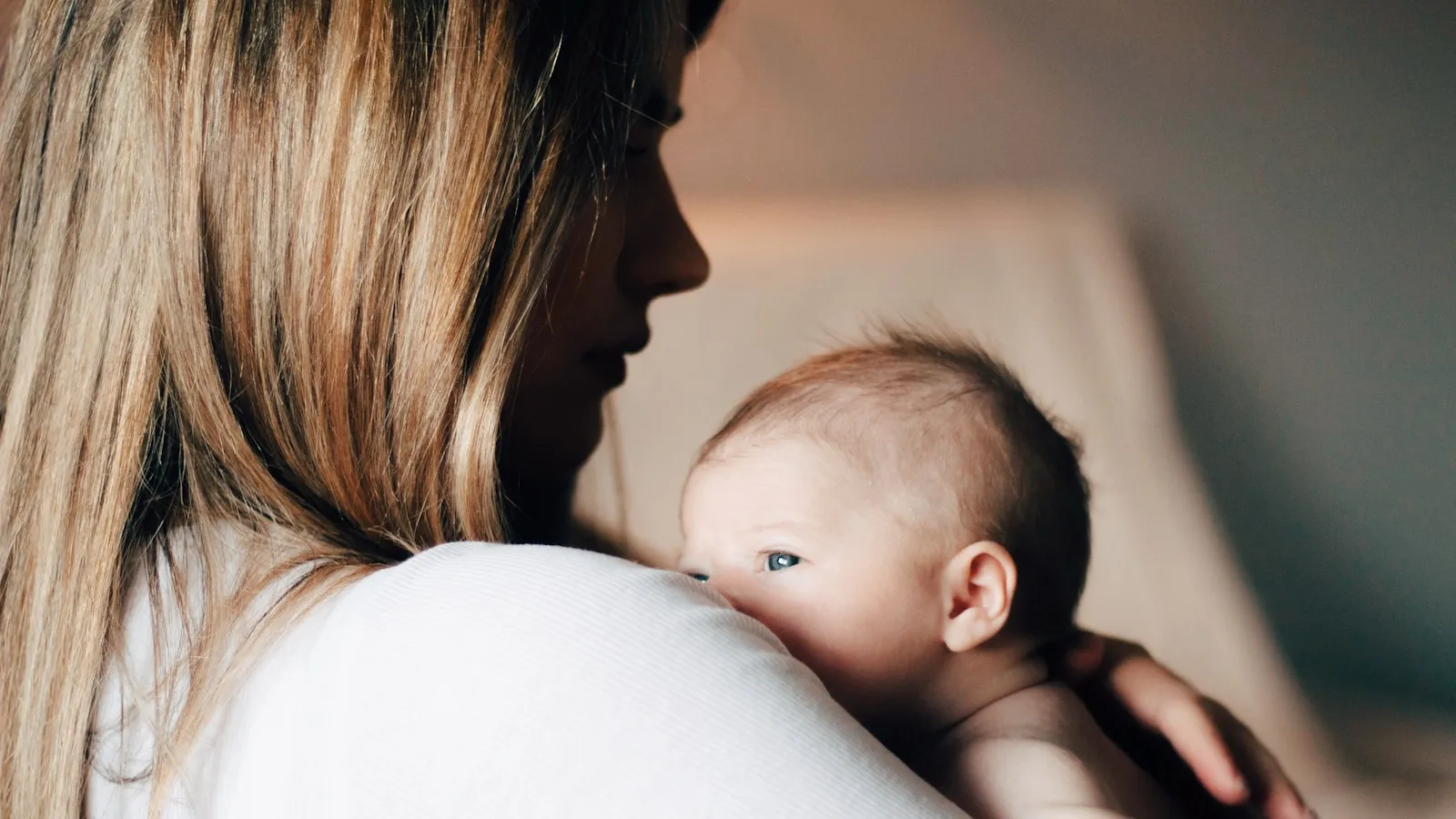 Jonge moeder houdt rustig haar pasgeboren baby vast.