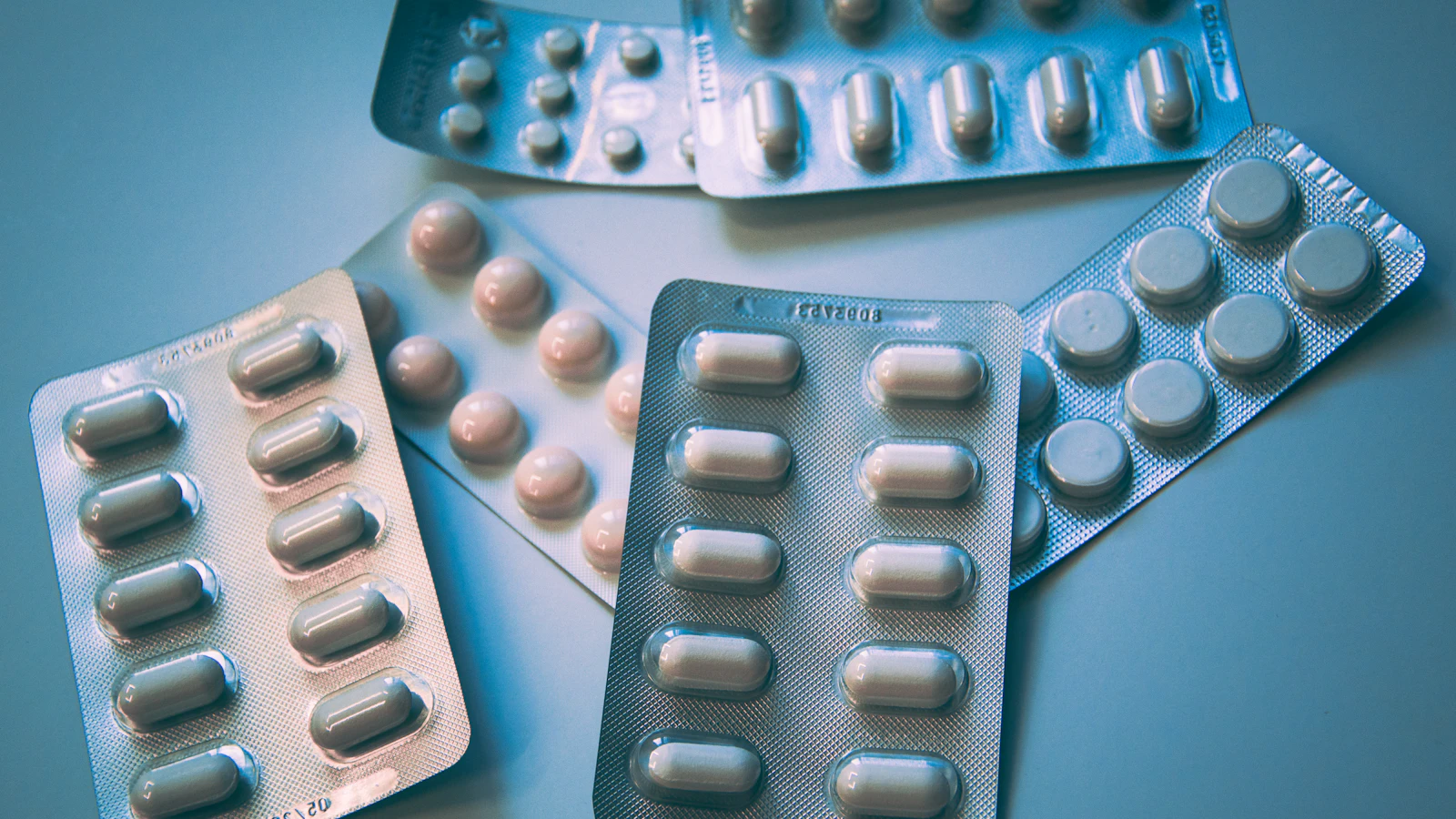 Verschillende doordrukstrips met tabletten en capsules op een blauwe ondergrond.