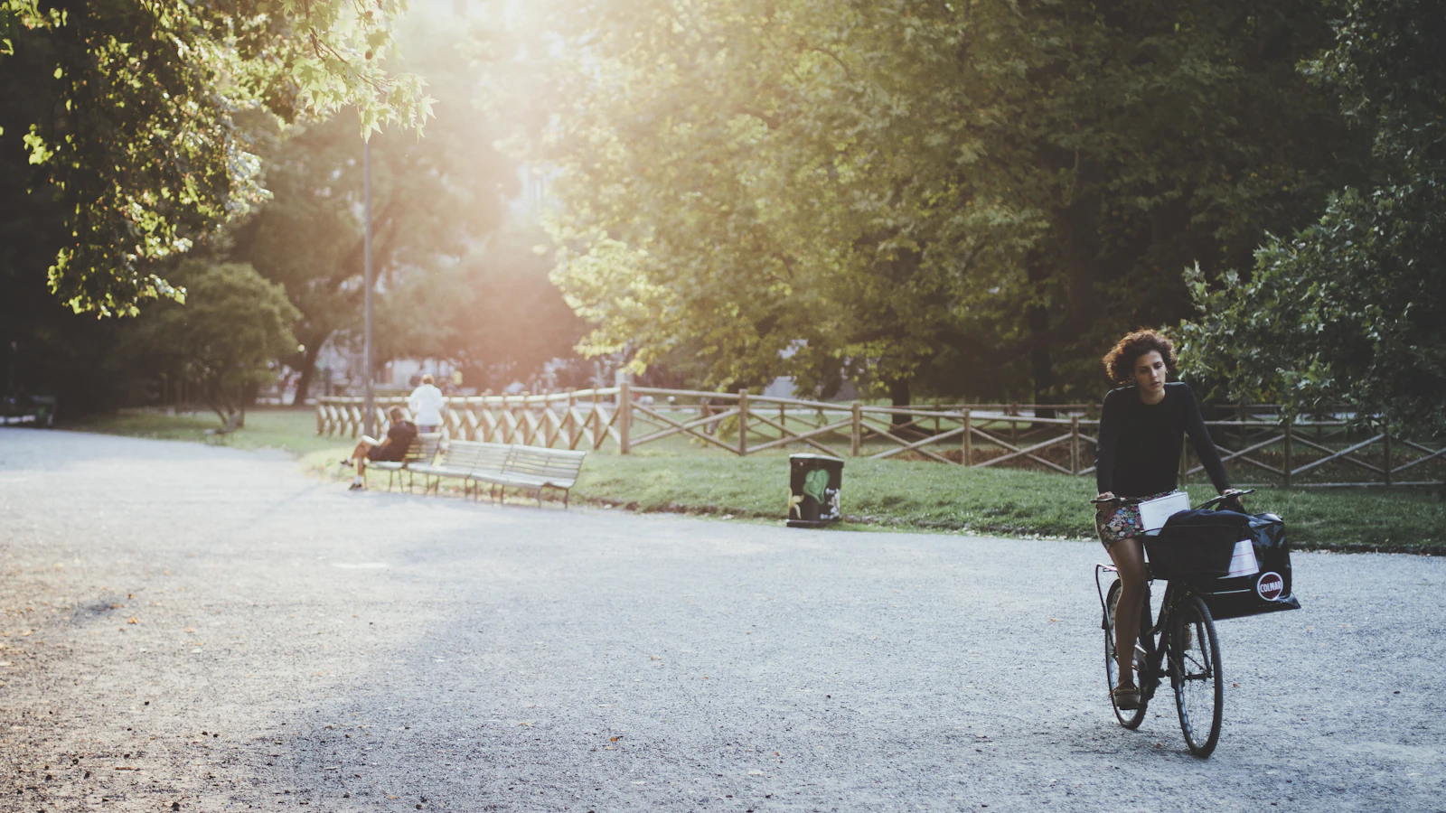 Vrouw fietst overdag door een zonnig stadspark.