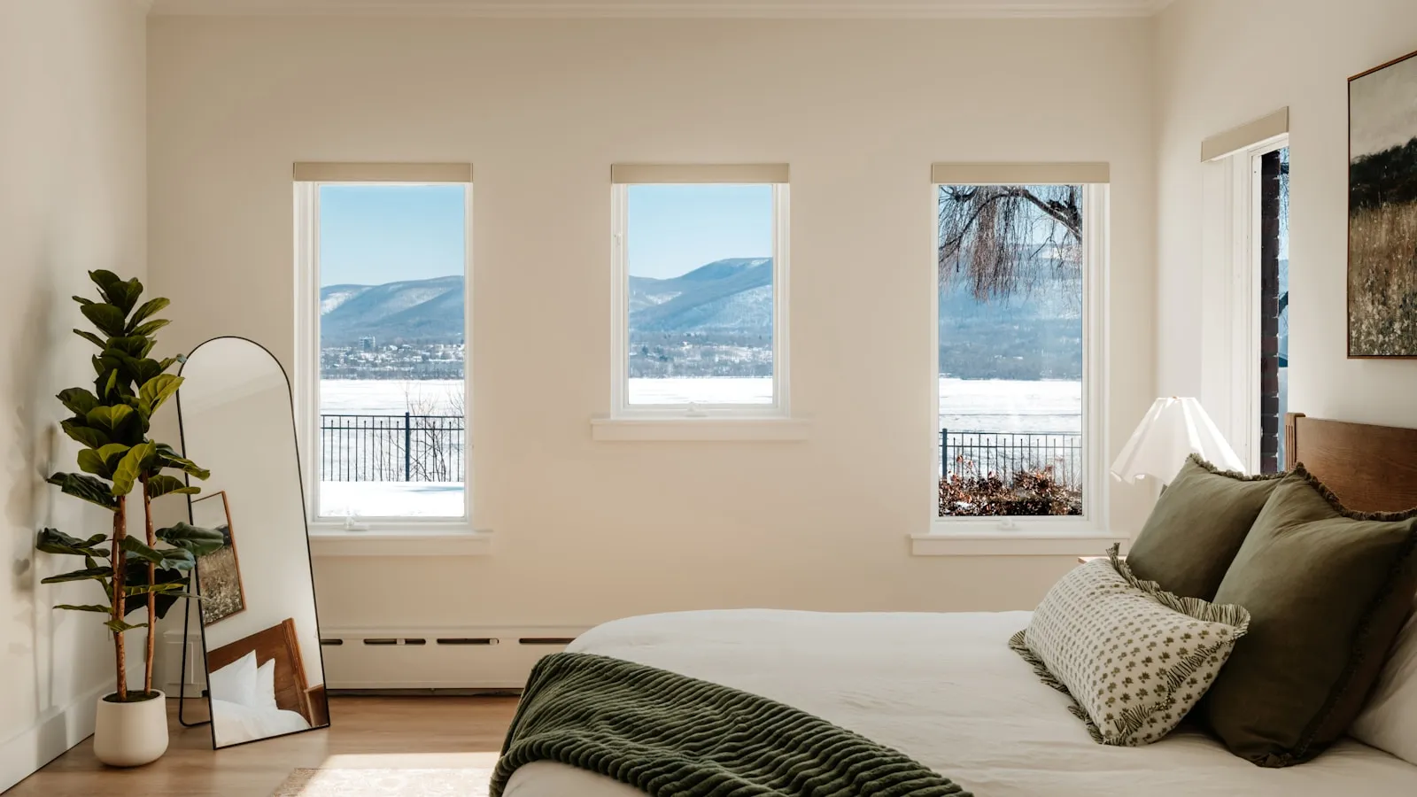 Opgemaakt bed in een lichte slaapkamer met uitzicht op besneeuwde heuvels.