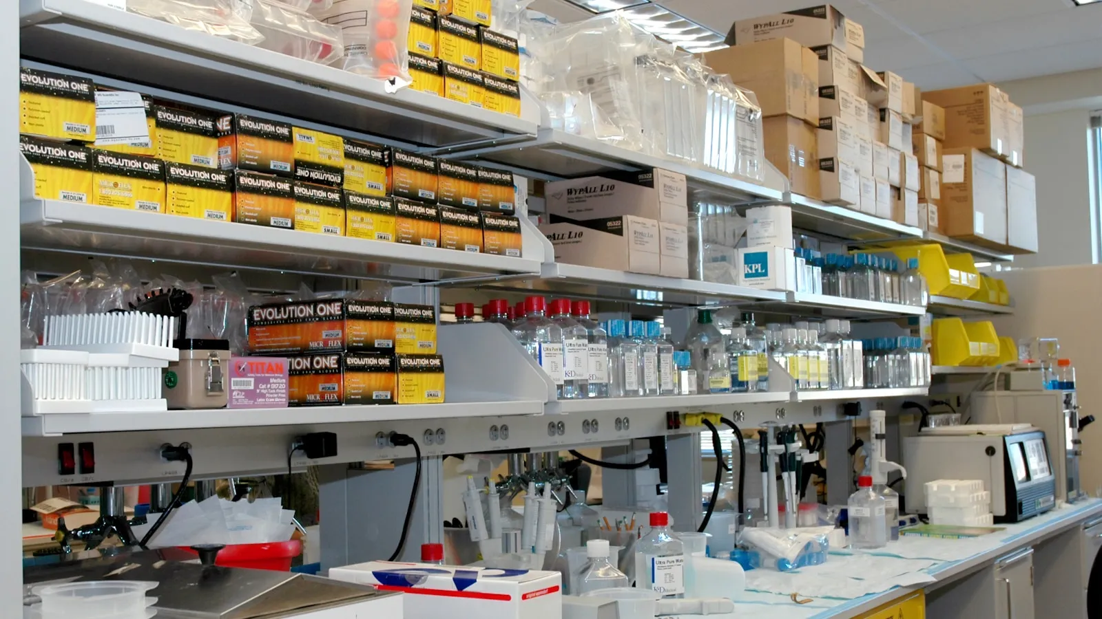 Een laboratoriumwerkbank met reagentia, pipetten en opslagdozen.