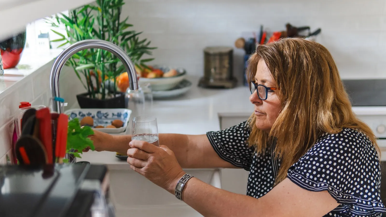 Zwangere vrouw loopt rustig door haar keuken met een glas water.