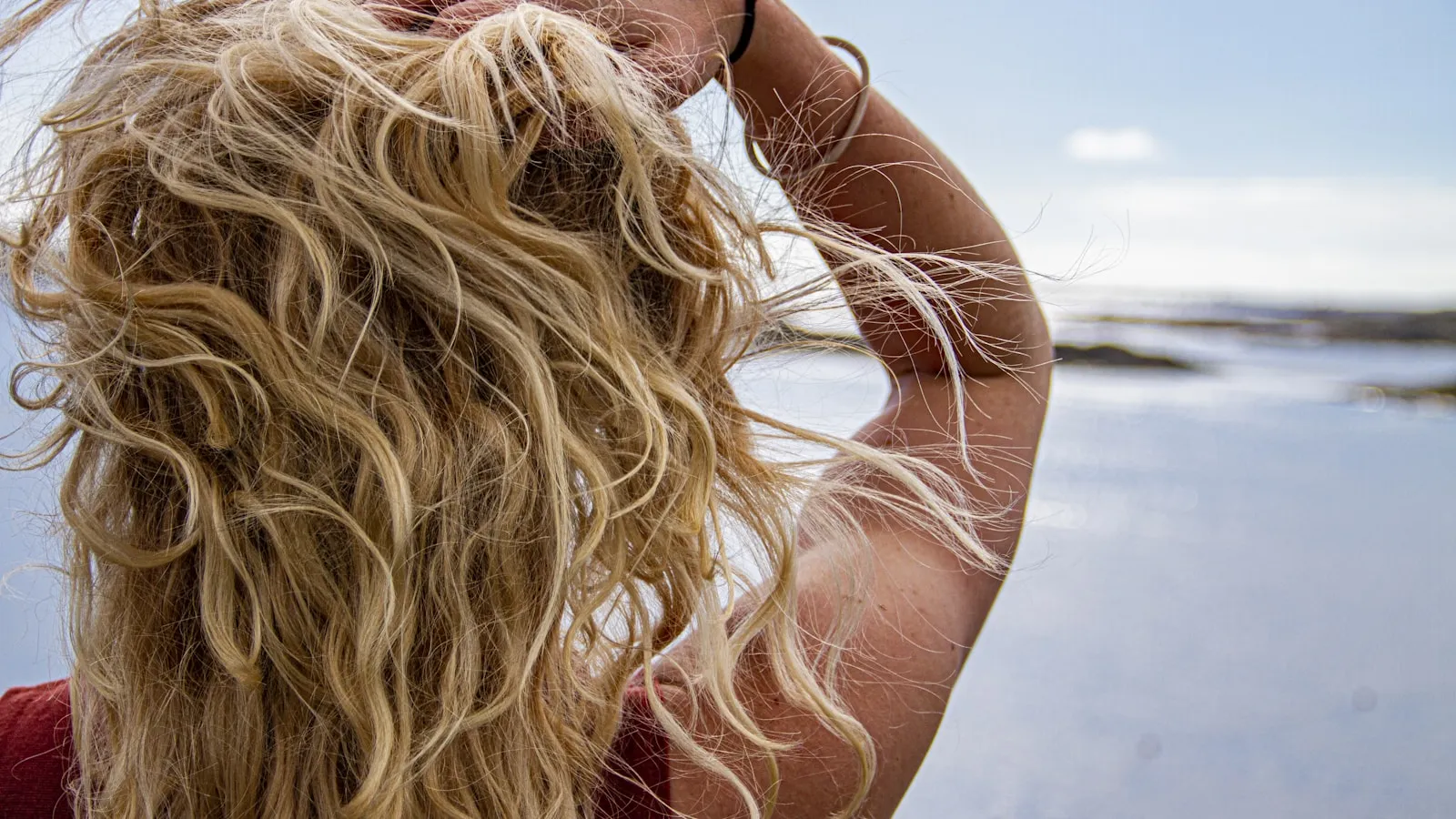 Vrouw buiten die met haar hand door haar lange blonde haar gaat.